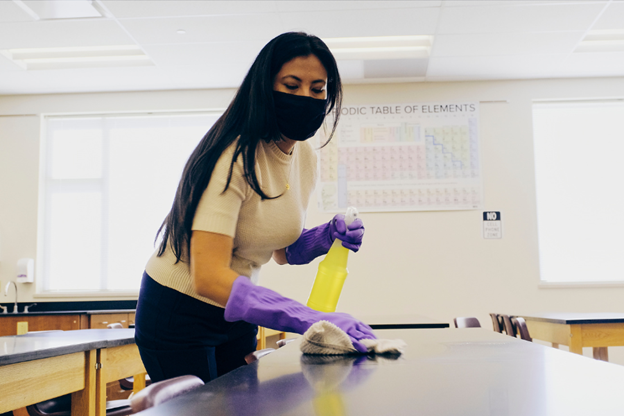 teacher cleaning classroom to show why universities should hire a commercial cleaning company