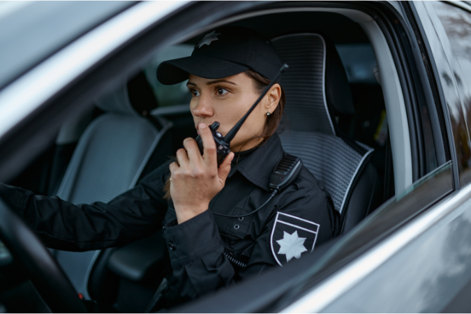 A security officer in their mobile patrol vehicle communicating over a radio and providing effective and versatile security.