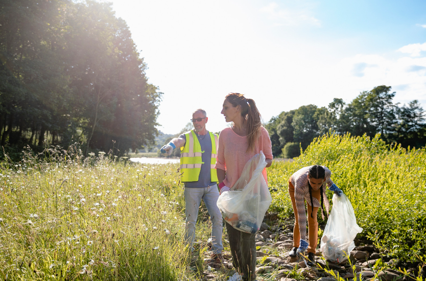 a man and two women cleaning litter in a field to show what local authorities need to know in order to eliminate fly tipping