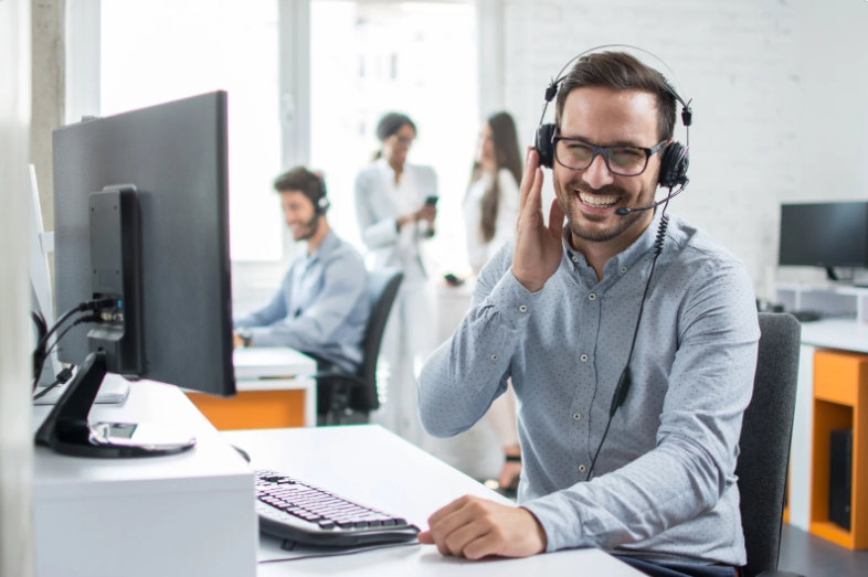 male call centre worker smiling whilst on a call to a customer to show what skills a staffing solutions service look for when finding call centre candidates