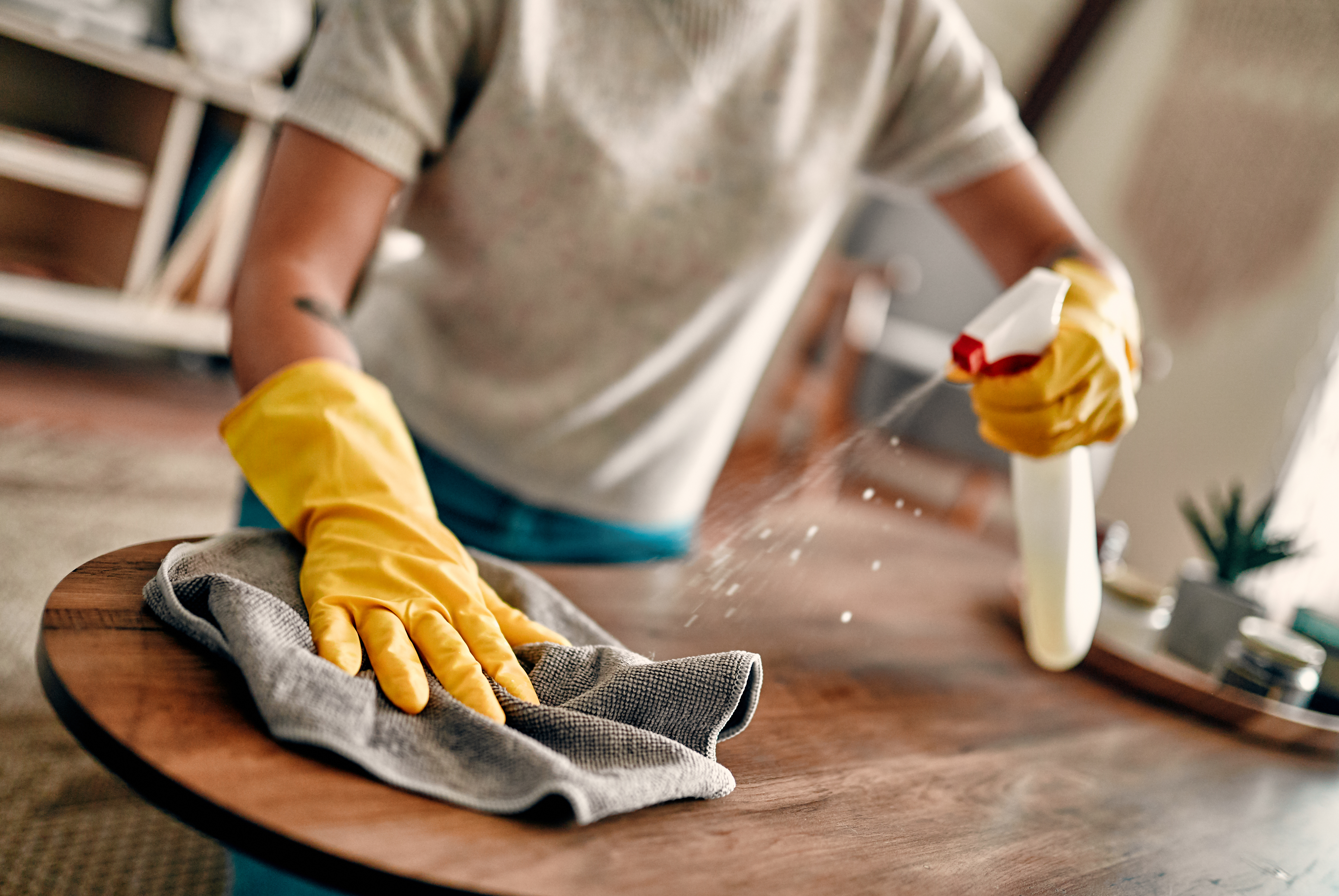 person cleaning a table with cleaning products to show why manufacturing companies should hire a cleaning service
