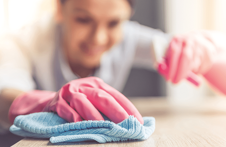Cleaner with pink gloves sanitising desk